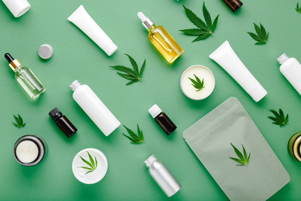 Flat lay pattern of hemp products and leaves on green background