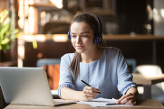 Focused woman wearing headphones using laptop in cafe