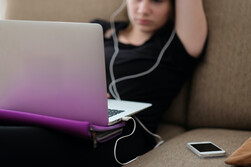 Photo of female student with laptop, headphones plugged into laptop