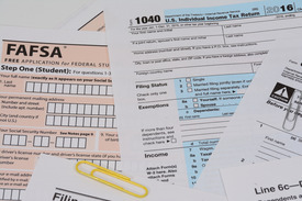 Image of paper FAFSA form and 1040 tax return document with a yellow paperclip