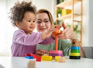 Female Early Childhood teacher working with a toddler in a classroom setting