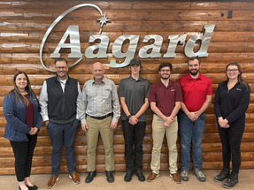 Seven people posing in front of the Aagard logo. 