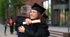 Female graduate embracing someone with a diploma.