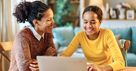 Mother and daughter smiling looking at a laptop.