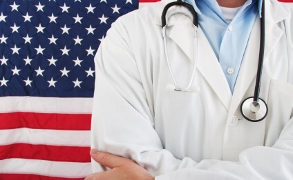 Picture of a man with a doctor's coat standing in front of an American flag