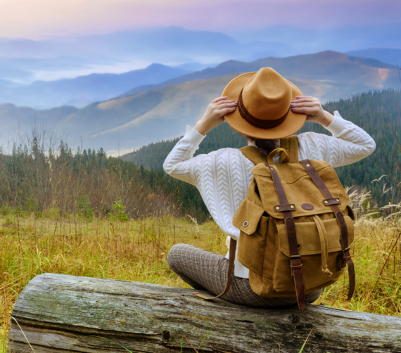 A woman sits on a log while hiking.