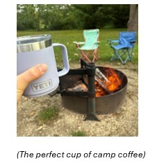 Picture of a coffee cup in front of a fire ring and two camp chairs