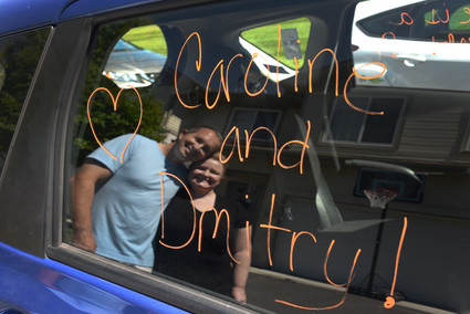 Dimtry and Caroline are reflected in the car window.