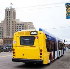 A BRT bus stopped at the corner of Lake and Chicago with Midtown Exchange in the background