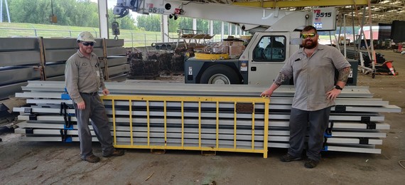 Machinist mechanics Nick Bernardy and Tony Bous in front of their revised basket hoist. 