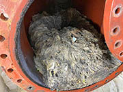 Dried clog of papers and grease in sewer pipe