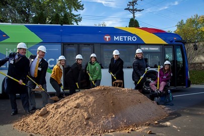 Elected and appointed officials shoveling dirt in front of BRT bus at groundbreaking event