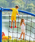 Children climb on net with lake in background