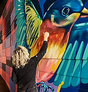 Artist Kada Goalen painting a transit station mural