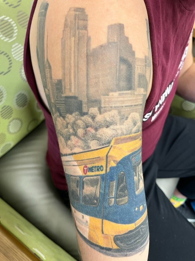 Jarred Paquin's arm tattoo depicting a Metro Transit LRV in front of the Minneapolis skyline.
