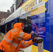 Worker putting up at sign at a light rail station.