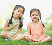 Two girls sitting on grass.