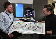 Two men talking at a desk.