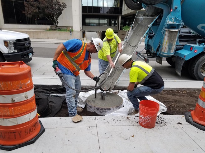 Crews pour concrete for light pole foundations at the 6th and Jackson Street station area in Downtown St. Paul