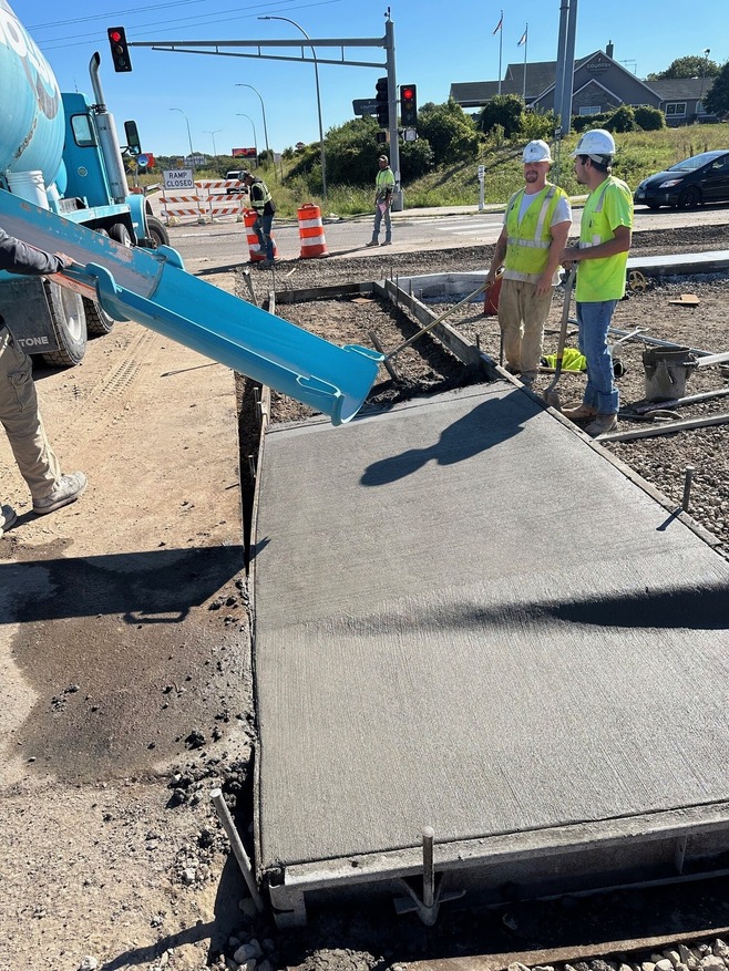 Crews pour concrete for sidewalk at Century Avenue/Highway 120