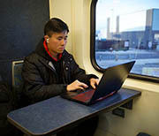 Train passenger working on laptop at a table.