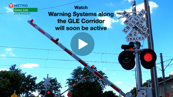 A photo showing railroad gates and flashing lights in front of a blue sky