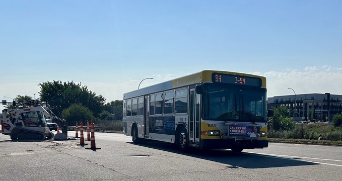 A Route 94 bus is seen navigating the construction of the Snelling Ave & I94 station construction. 