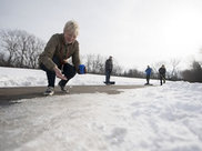 A woman spinkling salt on icy pavement.