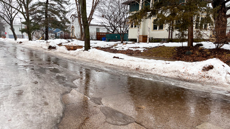 Rain creates a puddle on an icy streetcorner.