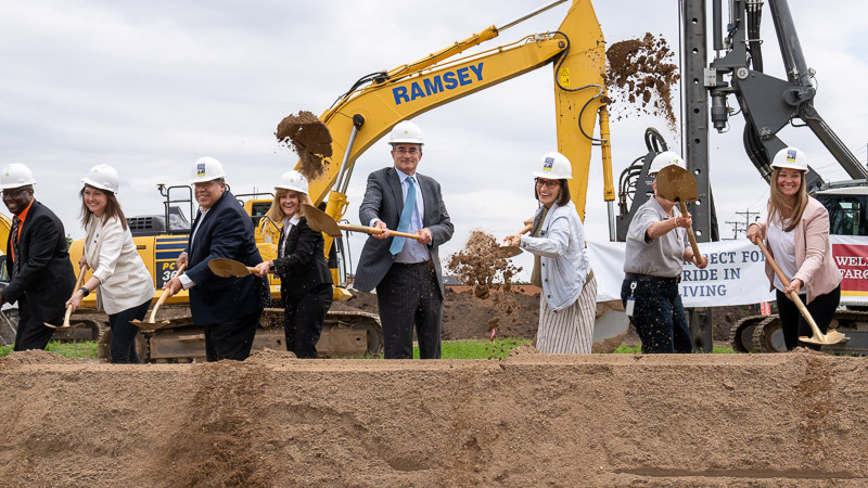 Political leaders and project partners shovel dirt at a groundbreaking ceremony.