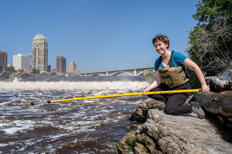 MWMO Environmental Specialist Evan Hanson collects a water quality sample from the Mississippi River.