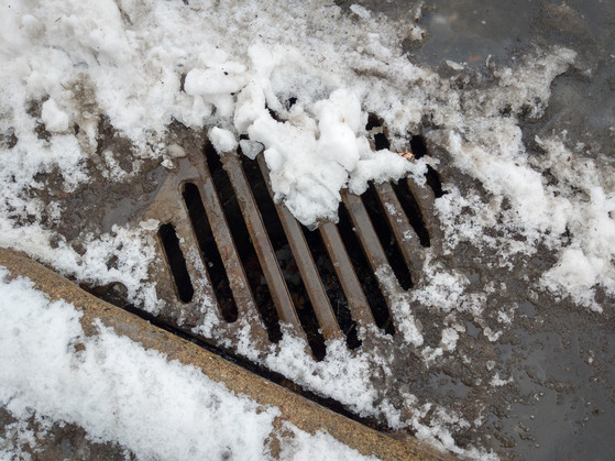 Partially melted snow and water around a stormdrain in Northeast Minneapolis.