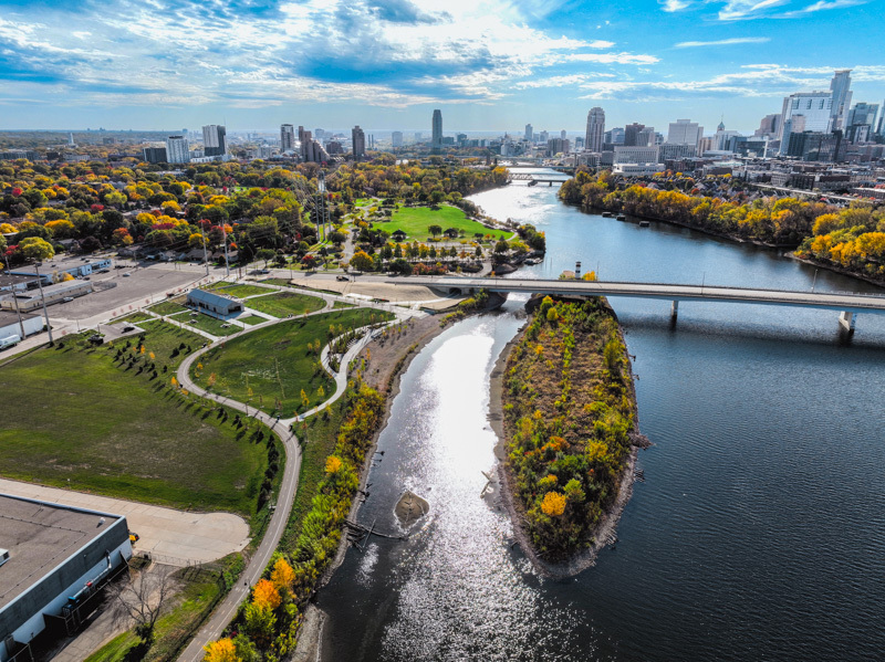 Aerial view of Graco Park and the Mississippi River, with restored riverfront habitat, trails, and downtown Minneapolis in the distance.