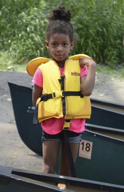 girl in life vest with canoes