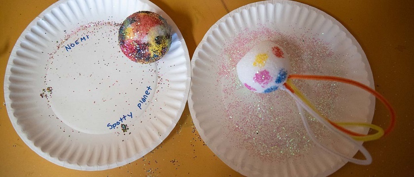 Art Through Science Camp paper plates with model planets decorated with glitter