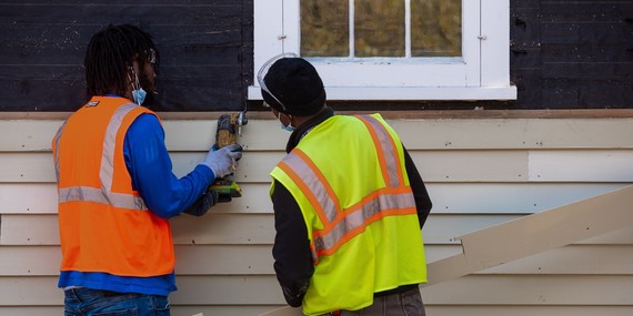 Two carpenters repair siding at the Ard Godfrey House