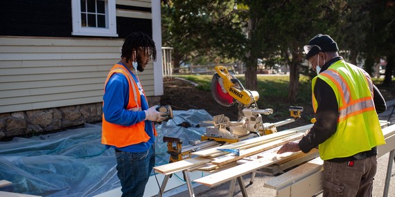 Two men work on siding repairs for the Ard Godfrey House in 2021