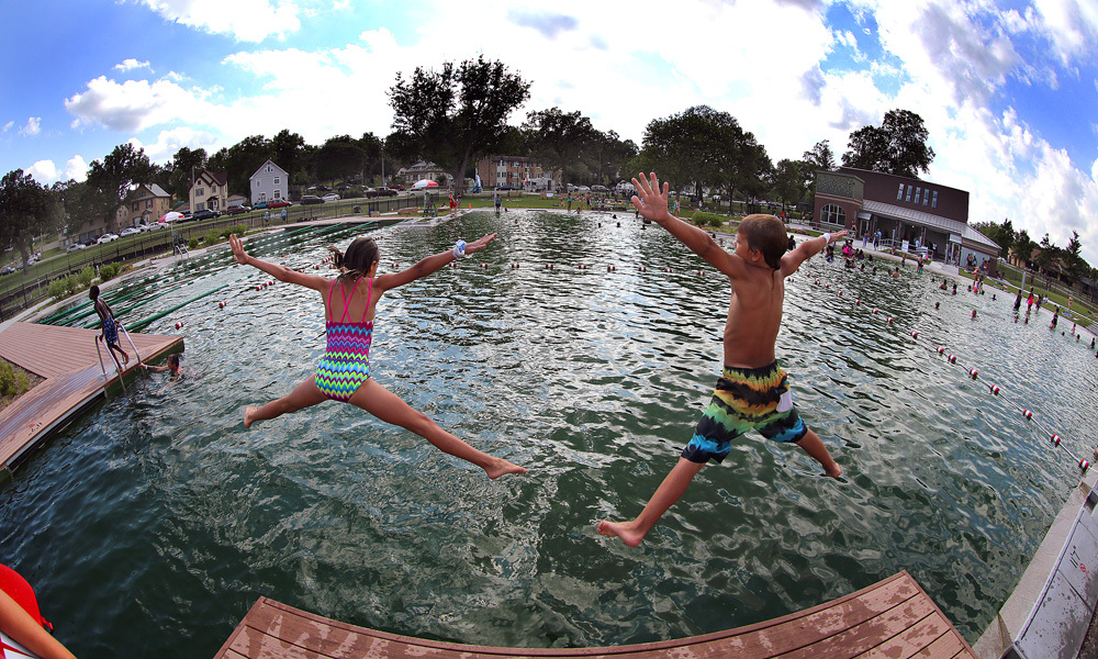 Two children jump into Webber Natural Swimming Pool