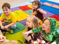 Kids sitting on a carpet with a naturalist