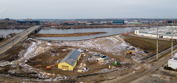 Graco Park from above showing the active construction site, framed park building and Minneapolis skyline on a cloudy winter day