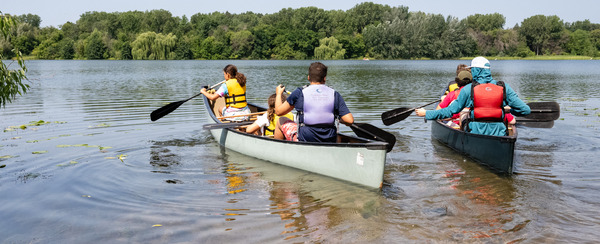 Two canoes with people paddling on a lake