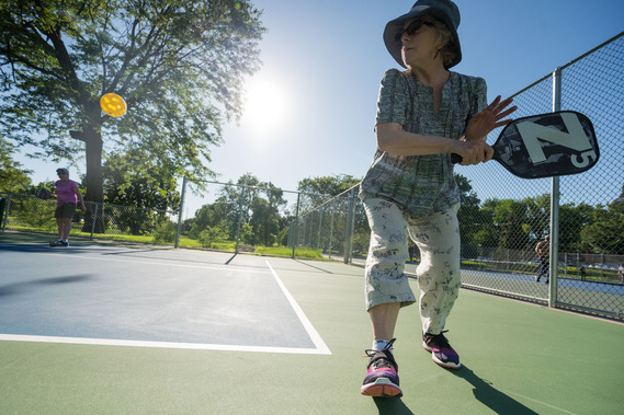 A close-range photo shows a person reaching for a backhand shot at new pickleball courts in Loring Park