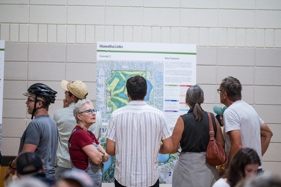 People stand in front of informational boards in the gym at Lake Nokomis Community Center during a Hiawatha Links Open House