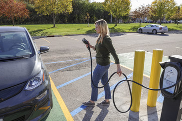 Woman using EV Level 2 charging station