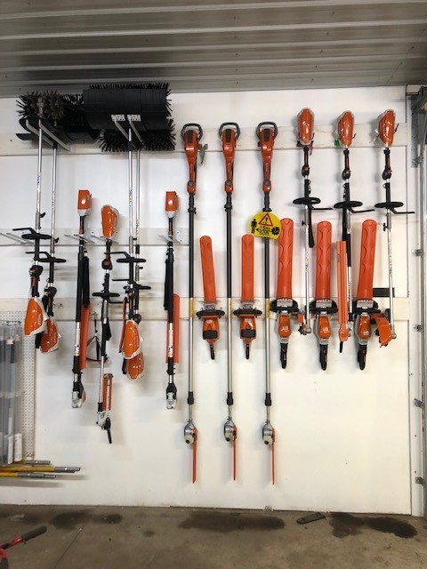 Battery-powered landscaping equipment hanging on the wall