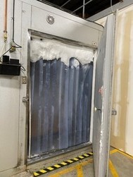 Entrance to a walk-in freezer with door, strip curtain, and ice build-up
