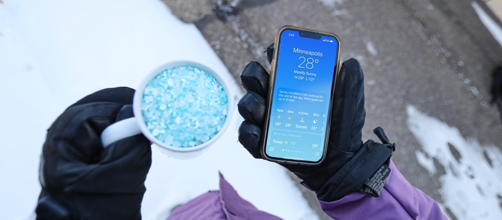 Salting sidewalk while checking temperature on phone