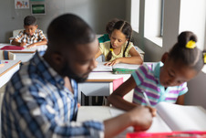 teacher in foreground helping student at desk
