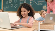 curly haired child working on a laptop