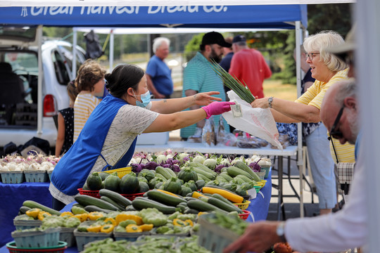 A Plymouth Farmers Market vendor sells fresh produce to a customer